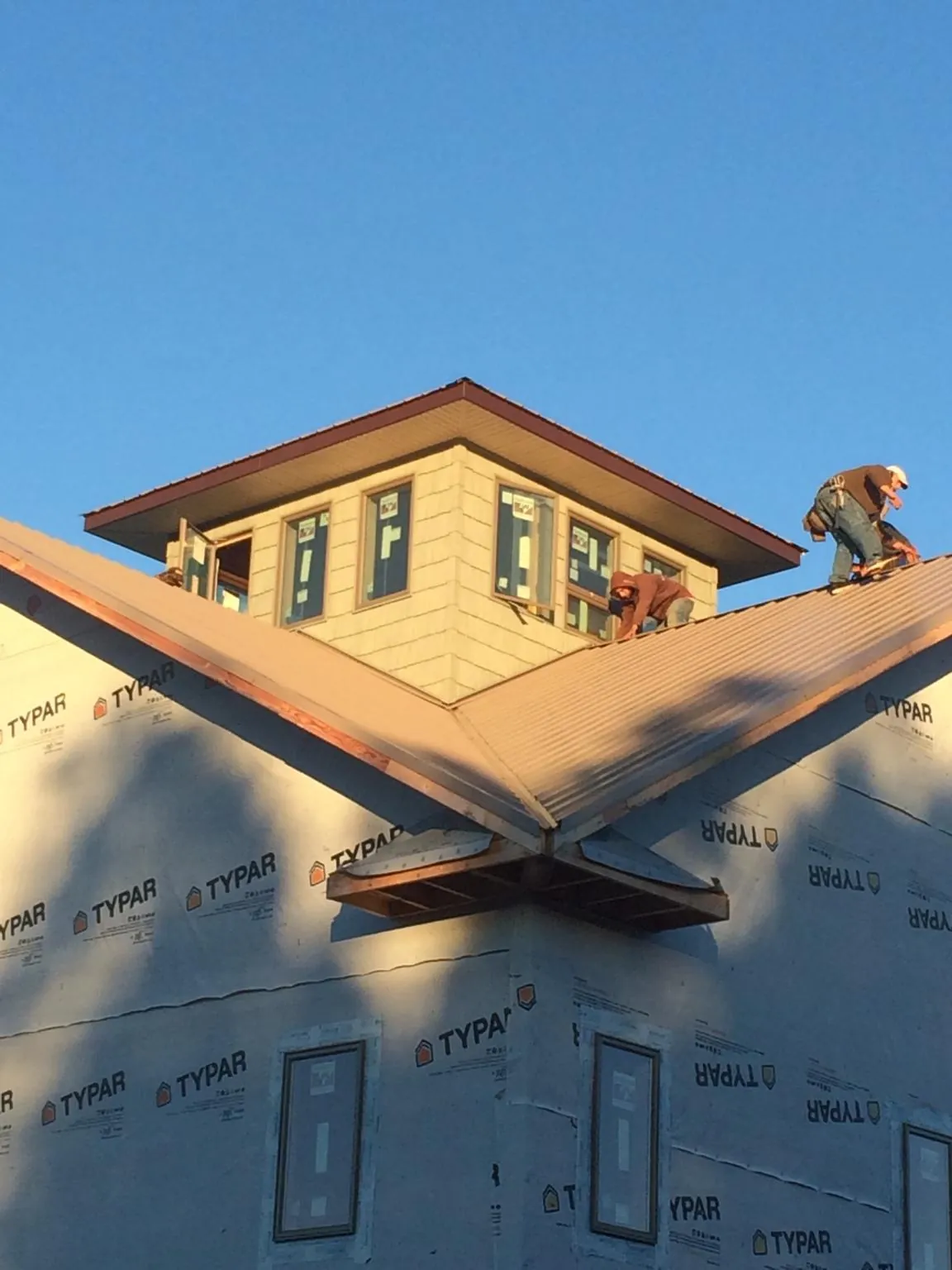 Roofers working around a rooftop cupola on a new metal roof at sunset — Roof Waterproofing in Freeport by Roofing Brothers